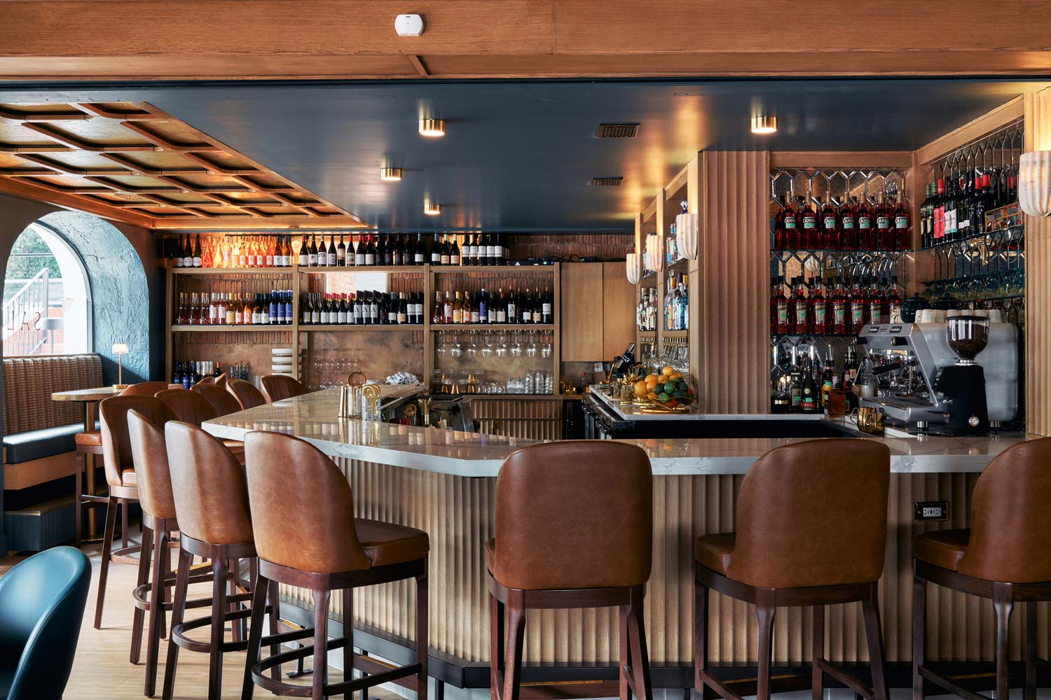 modern restaurant bar with high chairs and shleves of wine bottles